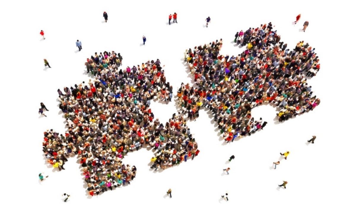 A birds eye view of a large group of people who are standing in the shape of two jigsaw puzzle pieces that are almost joined together.
