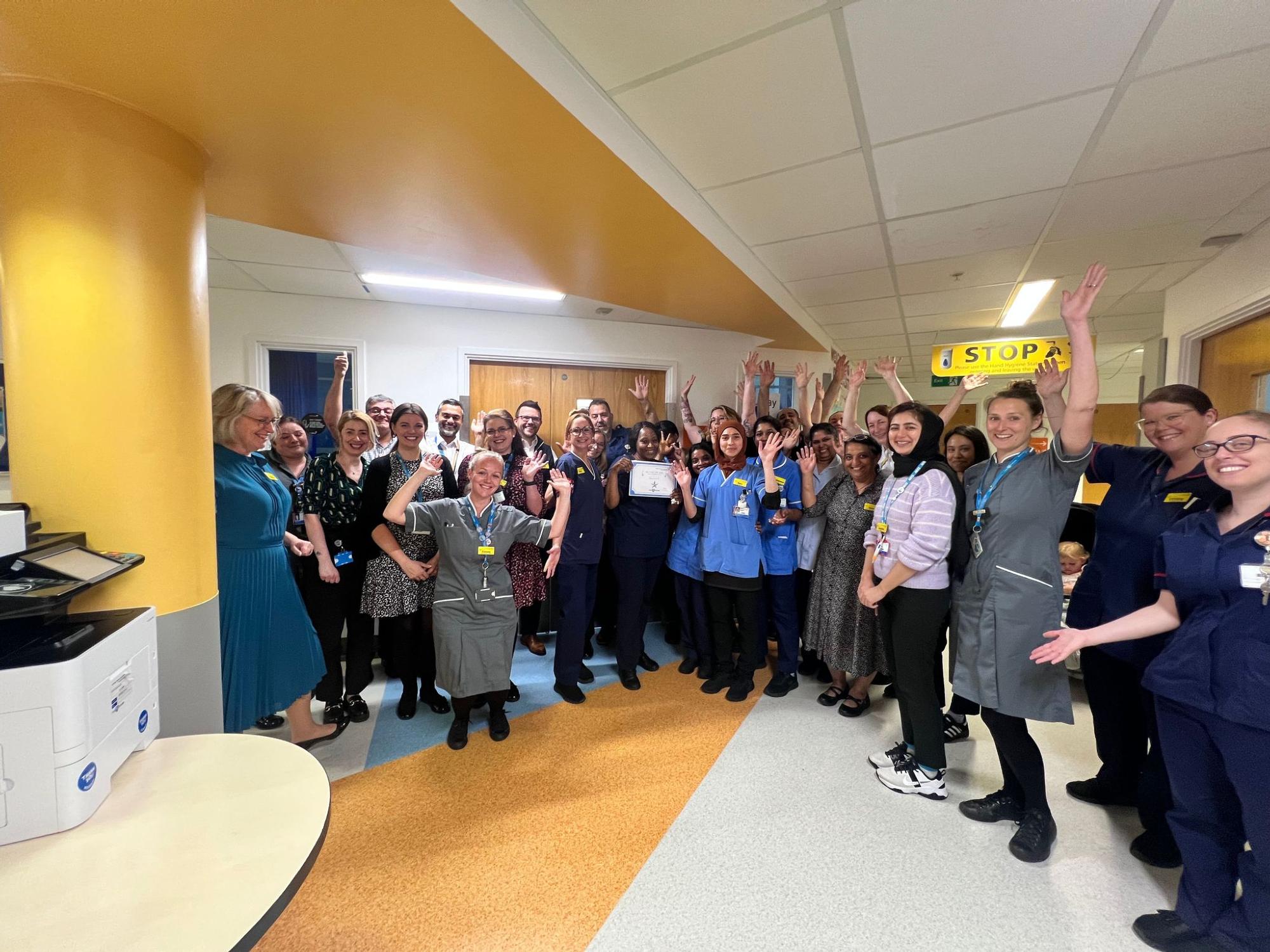 Picture of Harvest B ward accreditation, all of the ward sisters and staff members standing together cheering