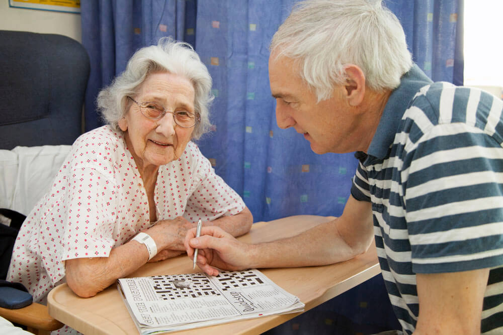 man visiting patient doing a crossword 