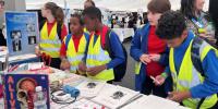 Primary schoolchildren in yellow hi-vis jackets looking at a stall